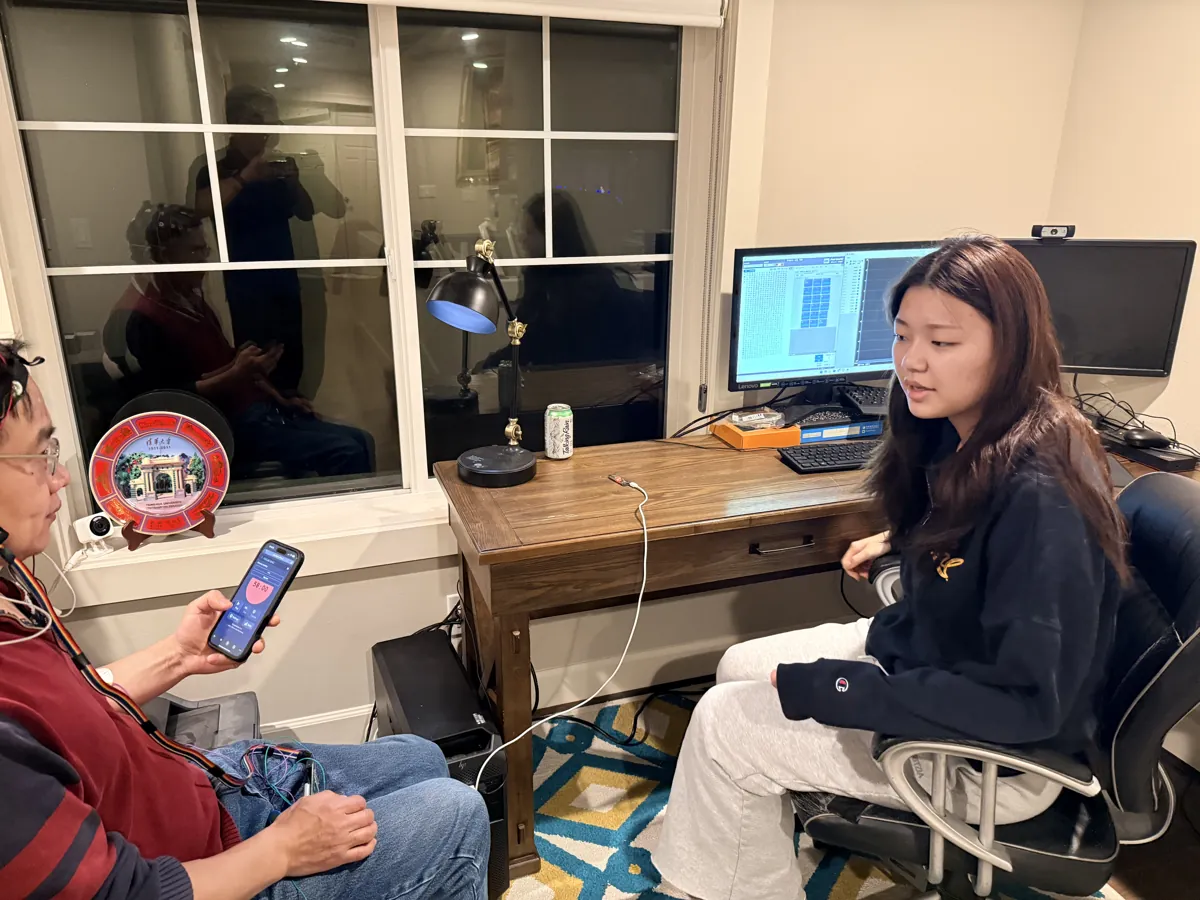 A student explaining an EEG brain-computer interface setup to a participant wearing a headset